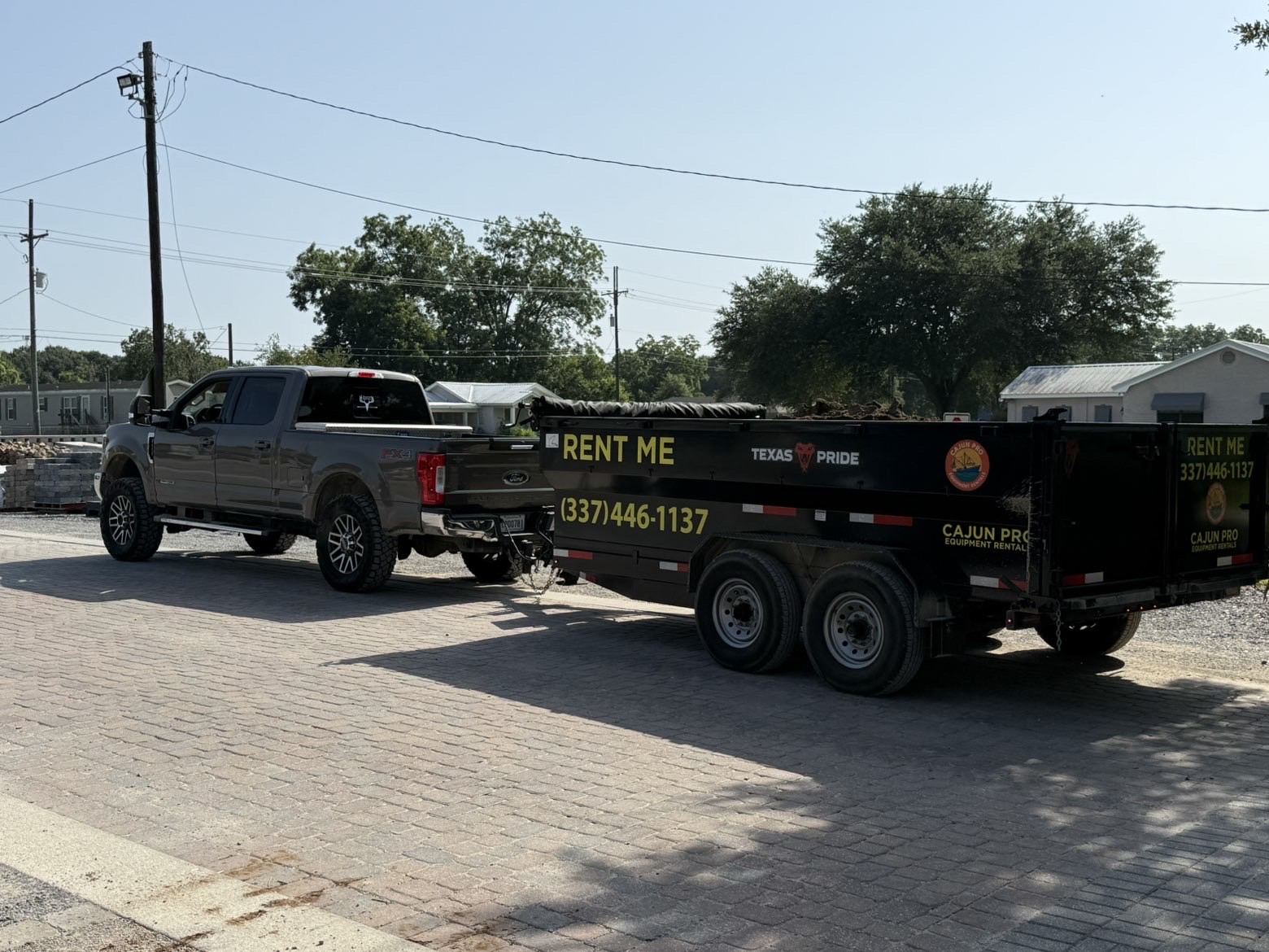 Loaded Cajun Pro dump trailer hitched to the truck on a paver drive