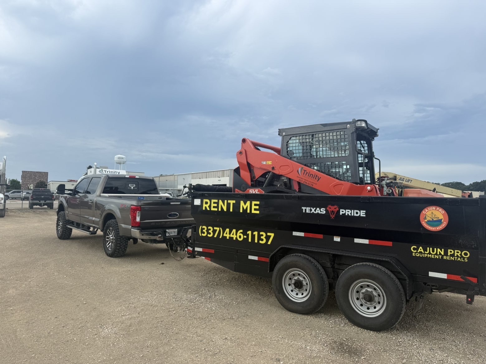 Skid steer loaded on the Cajun Pro dump trailer at a supply yard